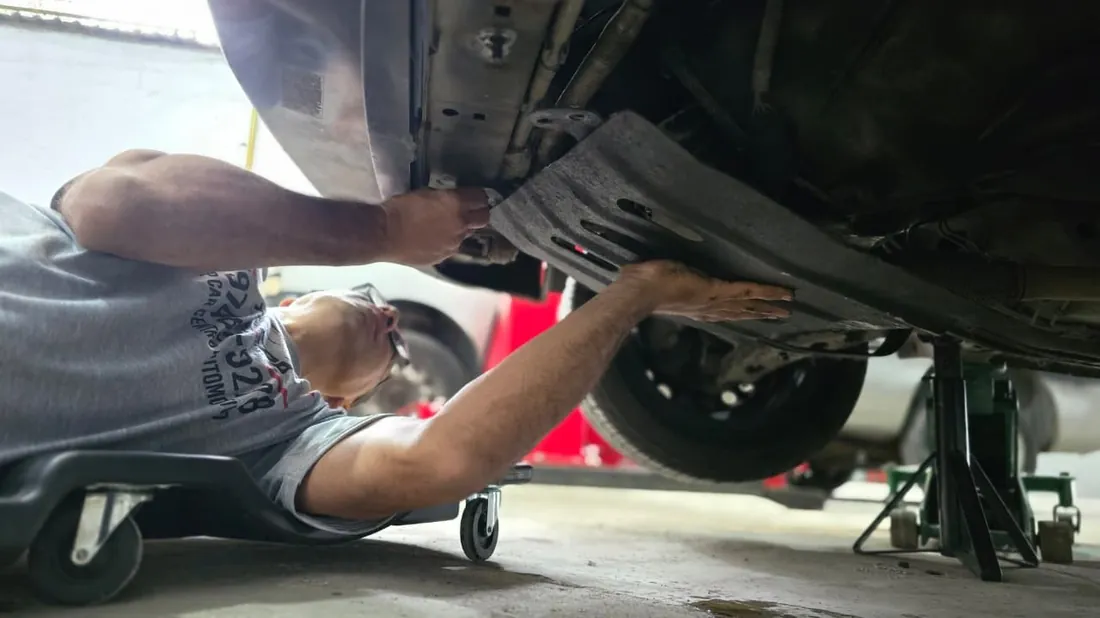 Mecânico trabalhando embaixo de um carro na Top Car